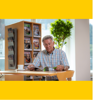 Ein Mann sitzt im Lesecafé und liest eine Zeitschrift.